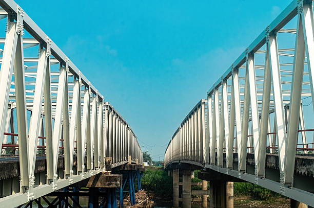 Two steel truss bridges span the Brantas River in East Java, Indonesia, supported by sturdy concrete pillars. Modern infrastructure landmark ideal for travel, construction, and urban development theme