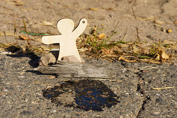 A wooden figure stands beside a small oil spill on a cracked surface, symbolizing the urgent need for awareness and action against pollution.