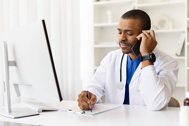 istock Focused African American doctor taking notes during phone conversation at work desk 2225749899