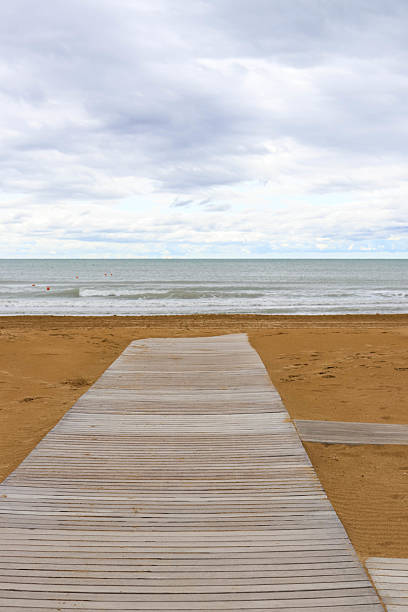 istock Wooden path leading to the sea under cloudy sky 2225752742