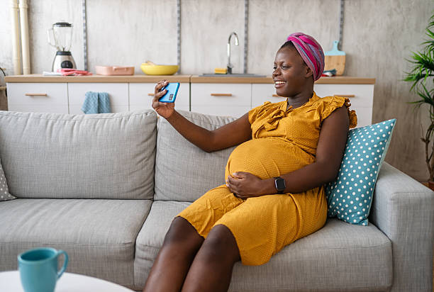 istock Happy pregnant woman using smartphone on sofa at home 2225753271