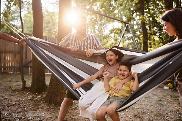 istock Cheerful kids having fun in hammock with their parents at the backyard. 2225756566