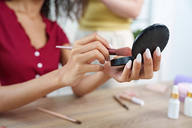 istock Makeup application. Woman applying blush with brush in front of mirror. 2225757418