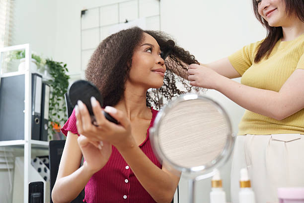 istock Hair styling. Woman getting hair styled while applying makeup. 2225757440