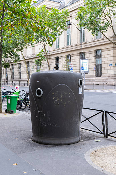 This urban capture shows a large trash container near bicycles, set against the architectural charm of a Parisian street, blending everyday city life with classic surroundings.