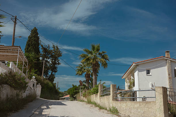 Traditional Greek village street with white houses palm trees and Mediterranean architecture under blue sky