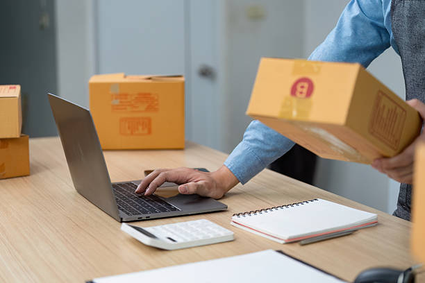 istock E-commerce logistics. A person managing packages and using a laptop for online business. 2225760598