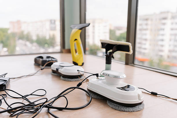 istock Several window cleaning robots, cordless window cleaner and window cleaning mop sitting on window ledge, cables attached and ready for cleaning large window 2225761007