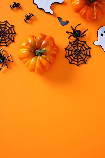 istock Festive flat lay with Halloween decorations on orange background: pumpkins, ghosts, spiders, webs, and bat 2225761795