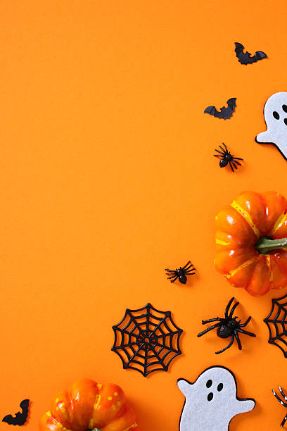 istock Halloween flat lay with pumpkins, ghosts, bats, spiders, and webs on vibrant orange background 2225762322