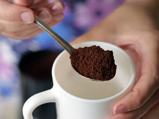 istock Hand Holding Spoon of Ground Coffee Above a White Ceramic Mug 2225765729