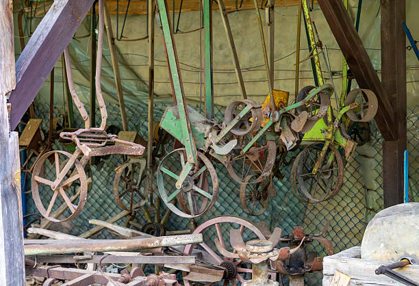 istock Old rusty agricultural machines and tools stored in a wooden shed, with visible wheels, frames, and metal parts 2225768160