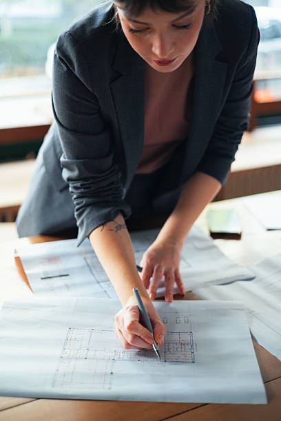 Architect Engaged in Planning Project at Workstation Reviewing Blueprints