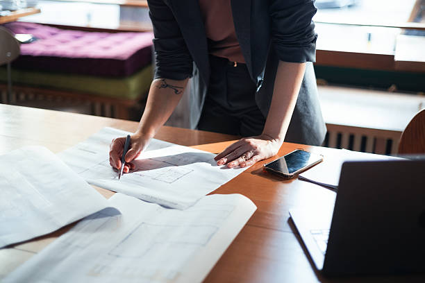 istock Businesswoman Reviewing Architectural Blueprints in Modern Office Setting 2225770374