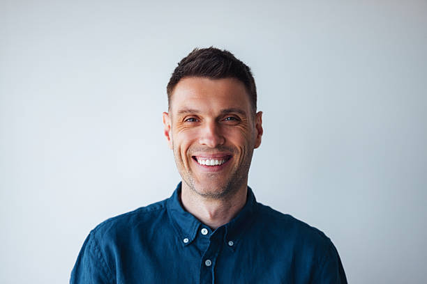 istock Smiling Man in Blue Shirt Posing Against Clean White Background 2225770894
