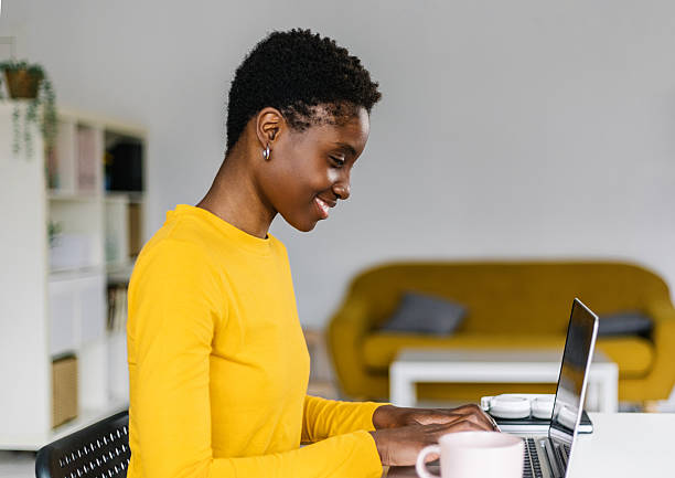 istock Smiling young african woman working on laptop computer from home office 2225771583