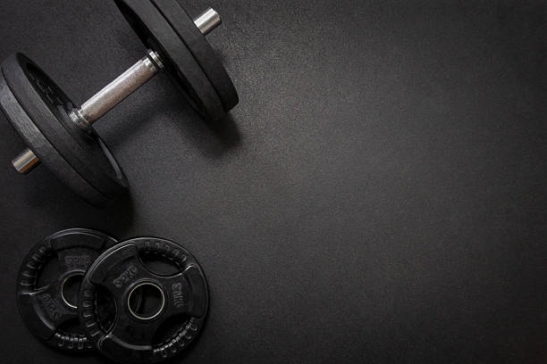 istock Dumbbell and weights resting on dark gym floor with copy space 2225775339