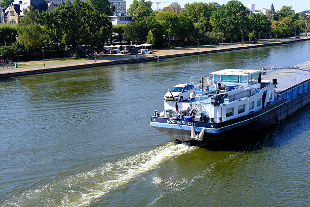 Main River Frankfurt, barges navigating, modern city skyline, bridge, green trees, clear blue sky, urban landscape, European process industry, German manufacturer, Frankfurt - June 14, 2023