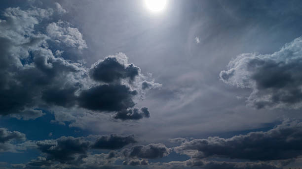 Dramatic sky with dark clouds and a bright sun illuminating the scene, creating a striking contrast. Perfect for backgrounds, weather themes, or artistic projects.