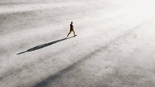 istock Businessman is walking on concrete surface with long shadow in bright sunlight, conveying concepts of business, challenge, future, and success 2225781092