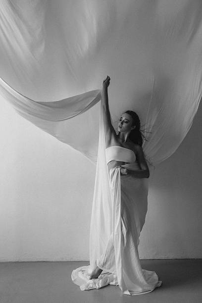 istock Elegant woman posing with flowing fabric in a minimalist setting 2225781549