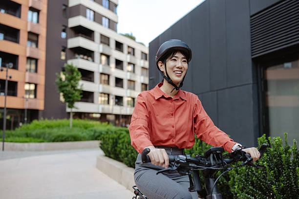 istock Smiling Asian person riding a bicycle in modern urban environment 2225781735