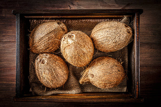 Fruit and vegetable themes:  Low key of coconuts in a wooden crate.