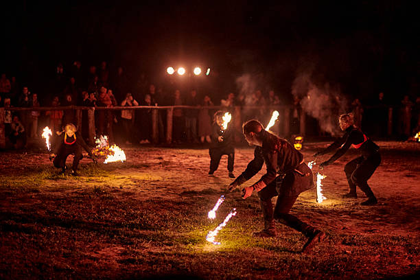 Kaliningrad, Russia - September 10, 2022 - Dancing fire show artists with fire poi at spectacular nighttime performance in dramatic light, fiery movements under night sky, spectators watching show