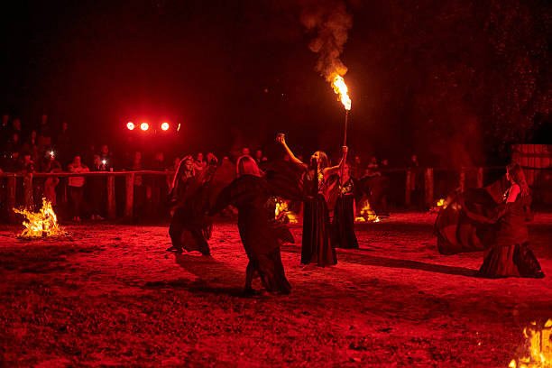 Kaliningrad, Russia - September 10, 2022 - Dancing fire show artists in an authentic dress at spectacular nighttime performance in dramatic light, fiery movements under night sky, spectators watching