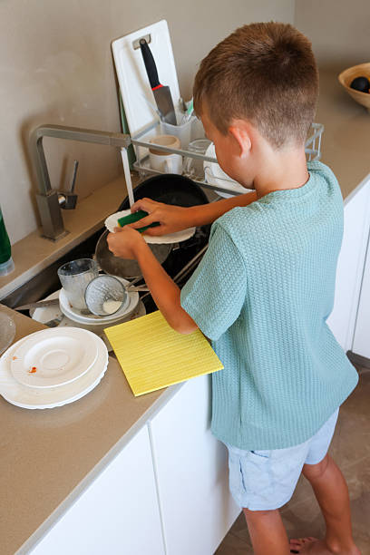 istock Child Washing Dish in Kitchen 2225782707