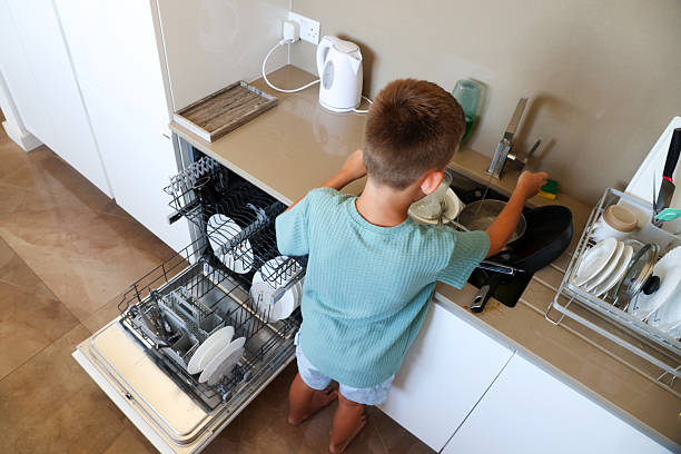 istock Boy Washing Dish Near Dishwasher in Kitchen 2225782718