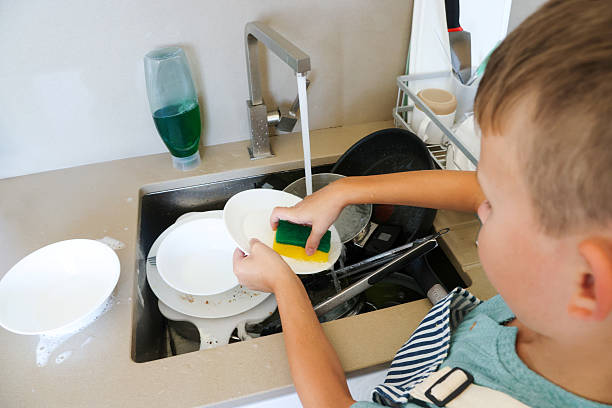 istock Boy Washing Dish at Kitchen Sink Using Sponge and Soap 2225783194