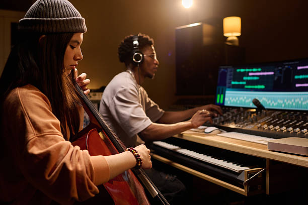 istock Young Latin Woman Playing Cello While Young Black Man Mixing Music in Studio 2225784862