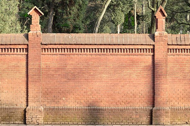 brick fence orange color material background frame work constructed pattern outside view with blurred garden behind wall
