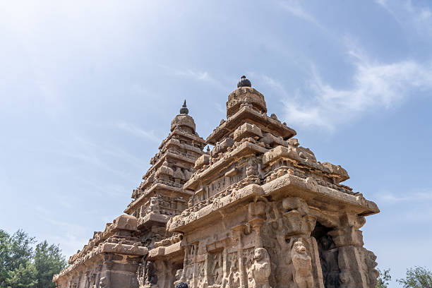 Two tall buildings with a blue sky in the background. The buildings are made of stone and have a unique design