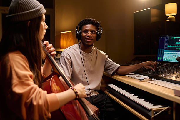 istock Young Black Man Operating Audio Mixer While Young Woman Playing Cello 2225787268