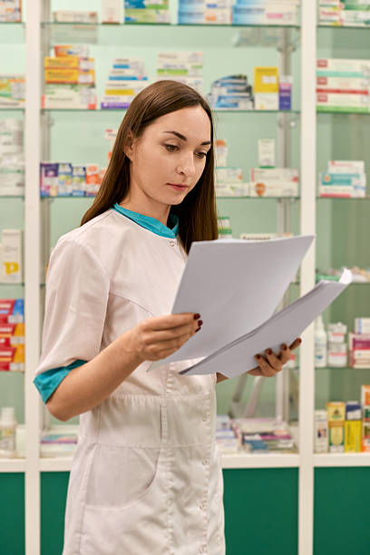 istock Focused pharmacist reviewing documents in bright pharmacy 2225787877