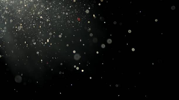 Floating white dust particles in light beam on black background