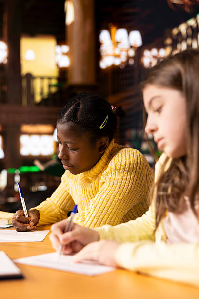 istock Diverse teens studying at a library table with textbooks and pens 2225789096