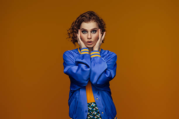 istock Surprised Woman in Blue Jacket Against Orange Background 2225789934