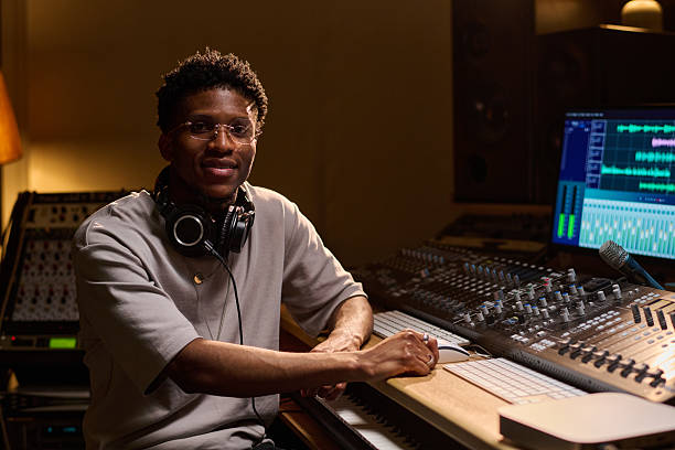 istock Young Adult Black Man Working at Audio Mixing Console in Recording Studio 2225793468