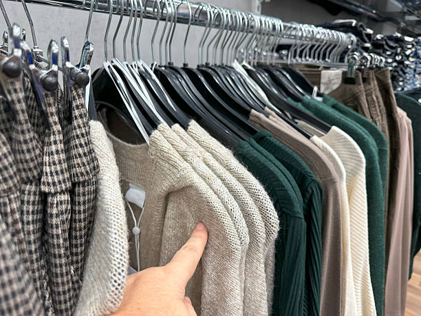 istock female customer browsing clothes in store, checking fabric, finding perfect size, affordable fashion, choosing outfit, affordable modern style, dresses on hangers, retail shopping, fashion sale 2225794648