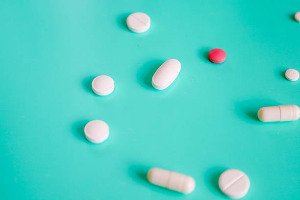 istock Various white and one pink pill, along with capsules, are scattered on a bright turquoise background, creating a minimalistic composition. 2225799297