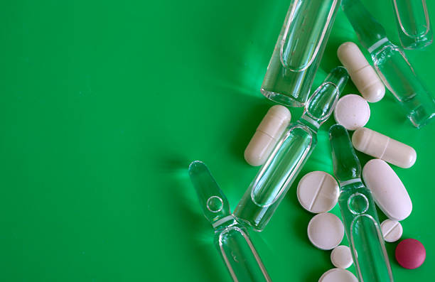 istock Transparent ampoules and various pills are scattered haphazardly on a bright green background, creating a dynamic composition. 2225799320