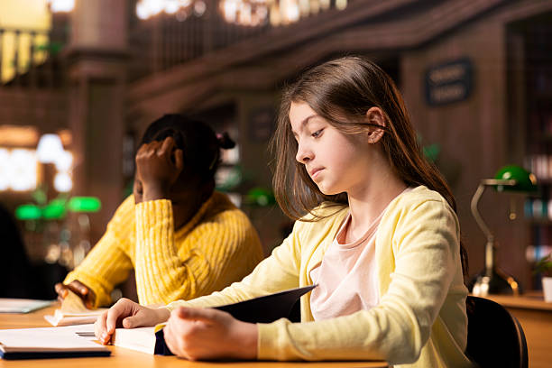 Teenagers immersed in reading literary works from the school library database