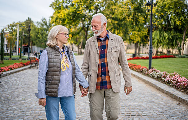 istock Happy senior couple holding hands while walking in a park 2225805663