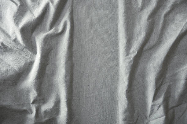 Detail of textured grey fabric wrinkled and ironed vertically in the center Top view.