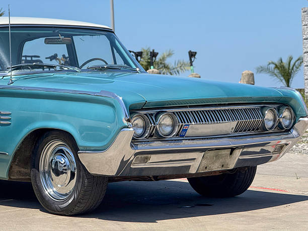 istock Vintage Turquoise Car Front. Chrome Grille, White Roof, and Tropical Backdrop 2225808406