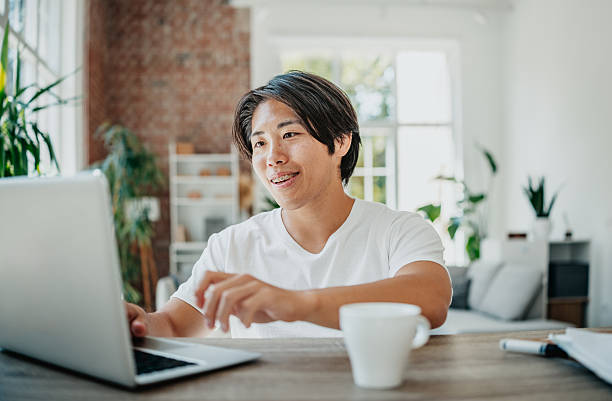 istock Young Japanese man engages in freelance work from a modern home office setting 2225808412
