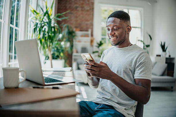 istock Young black man enjoying work from home while engaged with smartphone in bright living room 2225808868